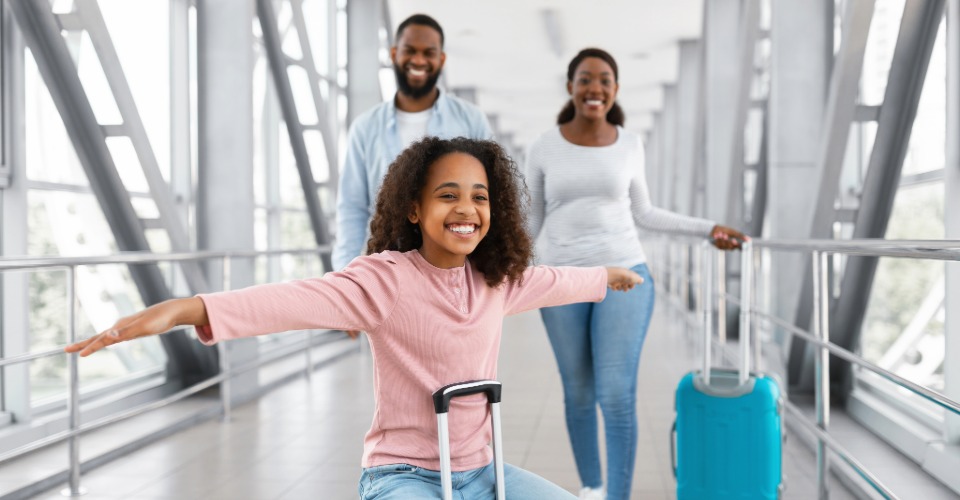 Família viajando com malas em aeroporto, representando férias em Prado com melhor custo-benefício para famílias